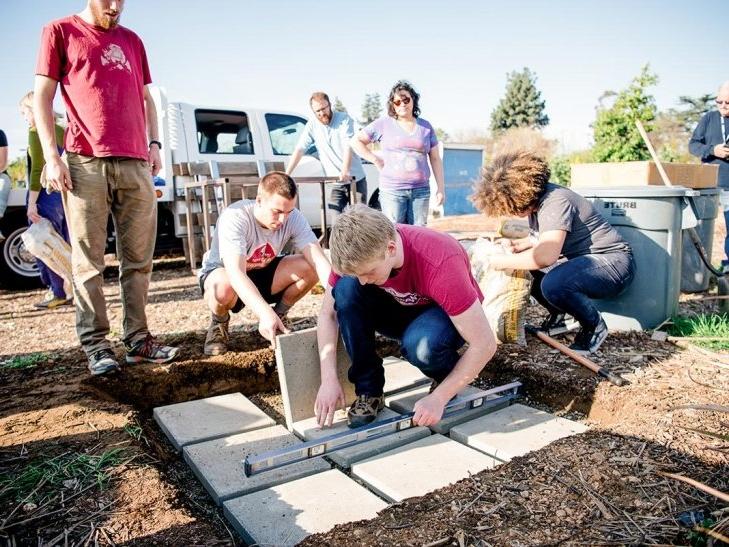 Students use tools to ensure cement squares are level for an oven in the Huerta del Valle garden.